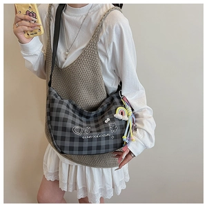 Détail du sac bandoulière en toile à carreaux avec graffitis et breloques perlées