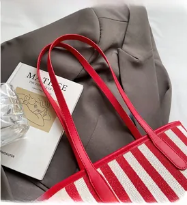 Detail of red and white striped canvas tote bag with reinforced leather handles