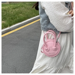 Pink lychee leather mini round crossbody bag with heart details and dual top handles