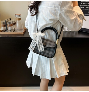 Detail of grey plaid square handbag with lace bow on a café counter background