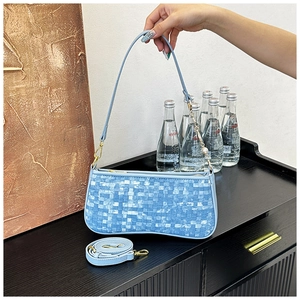 Detail of light blue woven underarm bag with gold zipper and adjustable shoulder strap