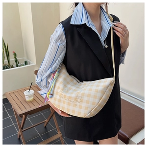 Détail du sac demi-lune à carreaux jaunes avec broderies et pendentif en corde