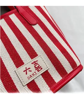 Detail of red and white striped tote bag showing woven fabric and leather brand tag