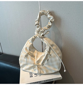 Dettaglio borsa hobo beige a scacchi con manico arricciato e decorazioni a fiocco