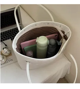 Vue de dessus d'un grand sac cabas blanc avec doublure rayée et objets du quotidien inclus