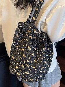 Floral drawstring bucket bag in black with yellow flowers and textured fabric