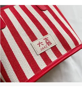 Detail of red striped canvas tote bag showing fine woven texture and logo leather patch