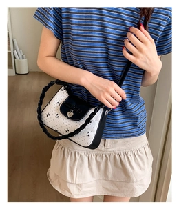 Détail d'un sac papillon avec pendentif en forme de cœur et poignée tressée