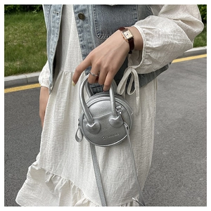 Close-up of a silver mini round bag with lychee leather texture and heart metal detail