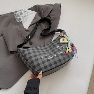 Détail du sac à carreaux gris avec breloque arc-en-ciel et logo mexicain imprimé