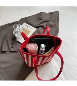 Spacious interior of red striped tote bag showing phone, umbrella and cosmetics