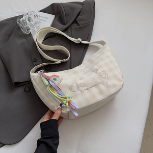 Détail du sac à carreaux avec broderie ours et cœur et pompon coloré sur la bandoulière