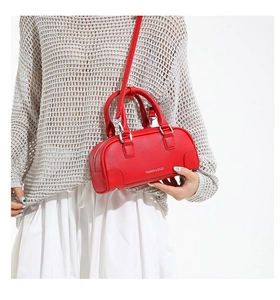 Détail du sac barillet rouge en cuir grainé avec texte blanc et bandoulière fine