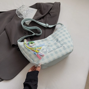 Détail du sac à carreaux bleu avec brodé d'un ourson avec bandoulière et pendentif à pampilles