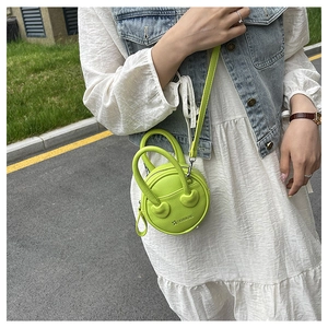 Detail of neon green circular mini bag with heart stitching and textured leather