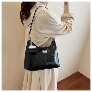 Détail du sac hobo en cuir verni noir avec bandoulière chaîne et fermoir métallique