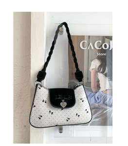 Détail du sac papillon blanc avec bandoulière tressée noire et pendentif en cœur