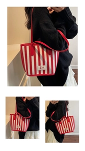 Detailed view of red striped canvas tote with leather straps and central brand logo patch