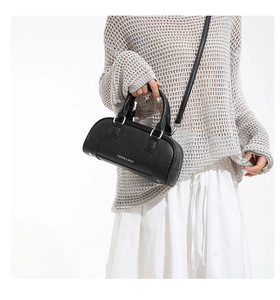 Gros plan du sac Boston noir à texture litchi avec texte de mode blanc et anses en cuir