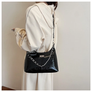 Gros plan du sac en cuir brillant noir avec boucle argentée et détail de chaîne