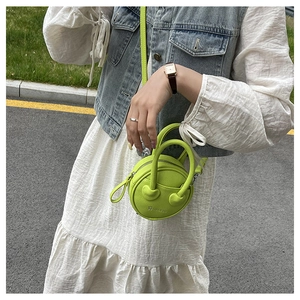 Detail of neon green round handbag with lychee texture and adjustable shoulder strap