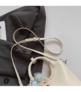 Detail der cremeweißen Leder-Einkaufstasche mit braunem Plüschbär-Accessoire