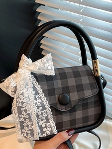 Fashionable checkered handbag with large white lace bow and black ring handle