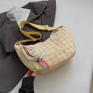 Détail du sac hobo à carreaux jaunes avec broderie ours et pendentifs colorés