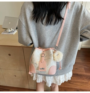 Detail view of pink and white bucket bag with sequins and a soft furry pompom