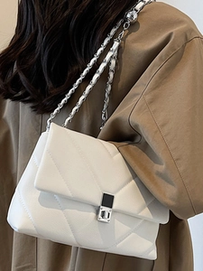 Elegant white quilted crossbody bag with silver chain strap and metal clasp worn on shoulder