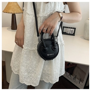 Detail of a black round mini leather bag with star embroidery and circular handles