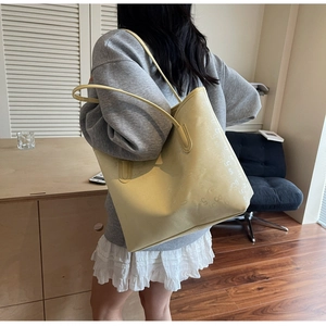 Détail du sac cabas en cuir crème avec des lettres embossées sur la bandoulière