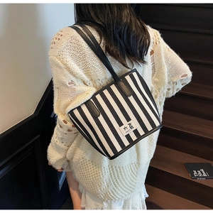 Close-up of black and white striped canvas tote bag with leather strap on a model shoulder
