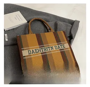 Detail des bestickten Logo-Bandes und der gestreiften Canvas-Textur der großen Tragetasche