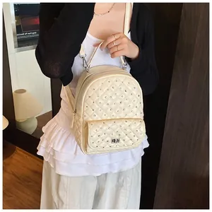 Close-up of beige quilted mini backpack with rhinestone studs and silver twist lock