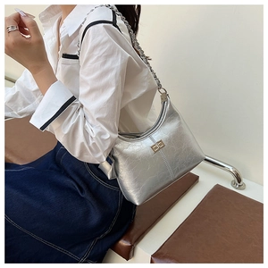 Detail van zilveren metallic handtas met gekraakt leertextuur en veilige draaisluiting