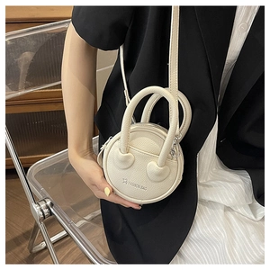 Detail view of mini round crossbody bag with lychee texture leather and heart logo