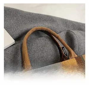 Detailaufnahme des gewebten Griffs und Markenetiketts der großen Shopper-Tasche