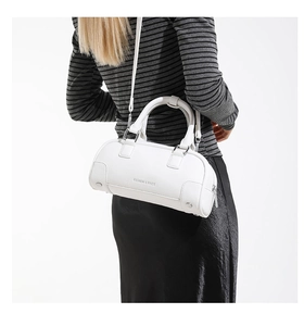 Vue détaillée d'un sac tonneau blanc avec boucles argentées et lettrage de mode