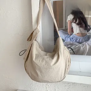 Detail view of beige dumpling bag texture with drawstring and adjustable strap