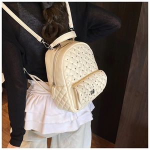Detail of a quilted off-white mini backpack with silver rivets and metal logo on the front