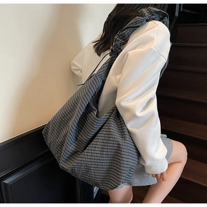 Detail of a large checkered tote bag showing the soft pleated texture on a model's shoulder