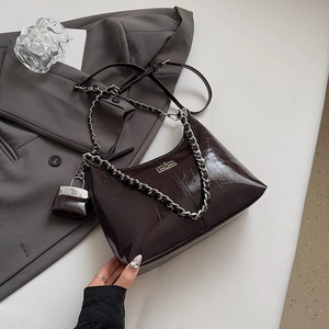 Détail du sac sous l'aisselle en cuir marron foncé avec chaîne argentée et mini pochette