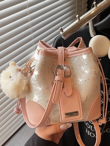 Pink and beige bucket bag with glitter texture and plush ball charm in natural light