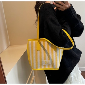 Detail showing yellow and white vertical stripes on a large knit tote bag with brand patch