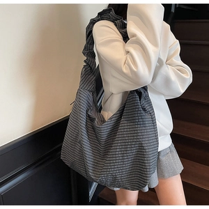 Close-up of pleated shoulder strap and plaid fabric on a large capacity hobo bag