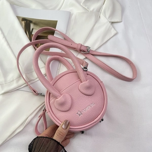 Detail of pink mini round bag with pebble leather texture and metal bottom studs