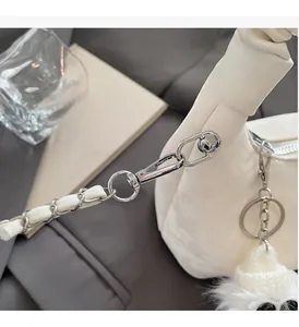 Detail of silver chain with white leather weave and plush ball charm on cloud bag