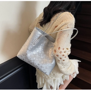Vue latérale du grand sac cabas argenté avec motif numérique porté à l'épaule sur escalier