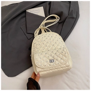 Close-up of quilted cream backpack with sparkling rhinestones and silver metal turn-lock
